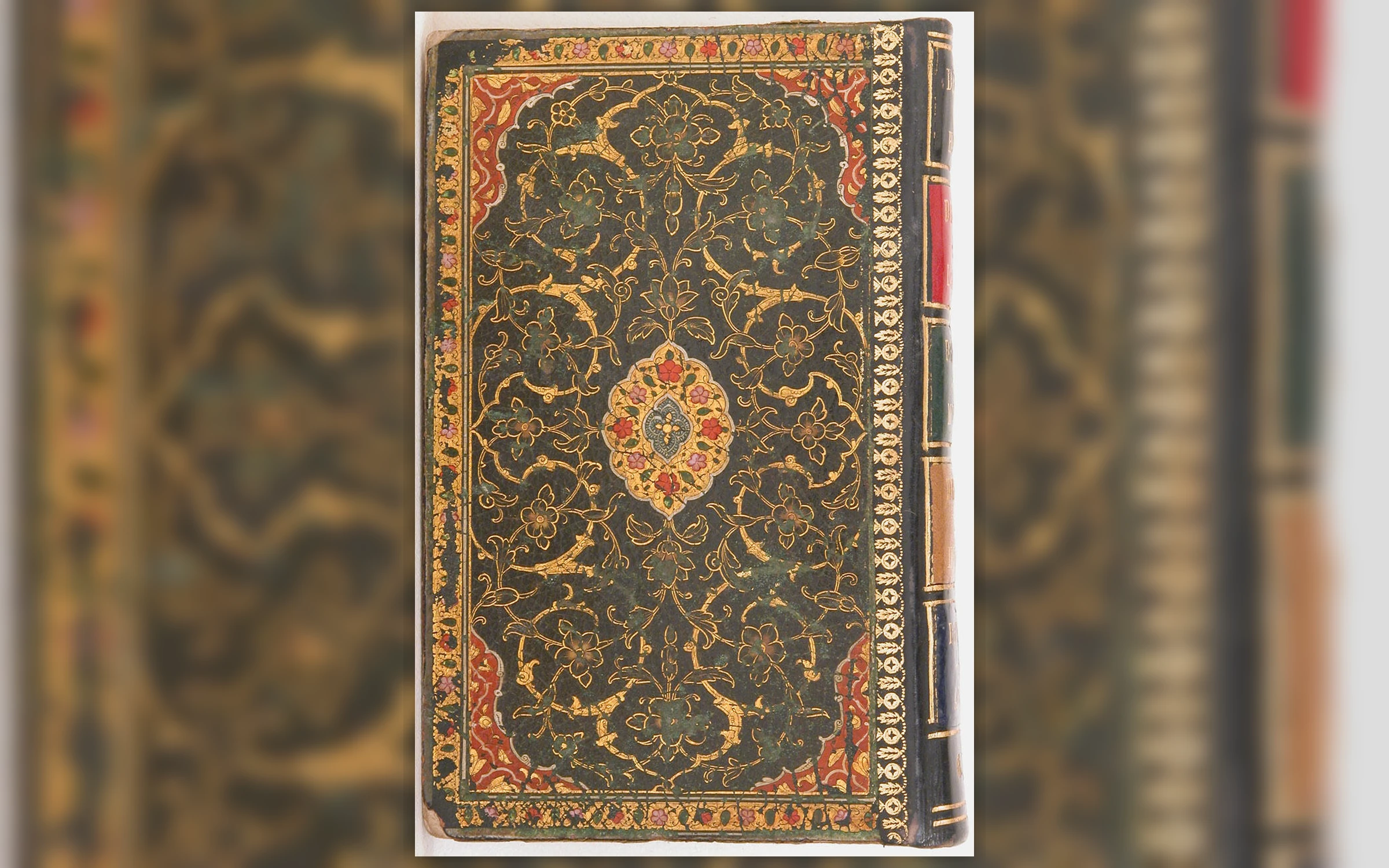Decorated dark leather binding of a seventeenth-century Persian poetry anthology, with gold floral ornament, red corner panels and a central painted medallion.